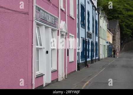 Farbenfrohe Gebäude im Portree Harbour auf der Isle of Skye, mit Touristen am anderen Ende der Quay Street, die eine Sea Tour buchen Stockfoto