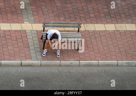 Junge Person, die in der Türkei auf einer Bank sitzt und mit seinem Handy spielt Stockfoto