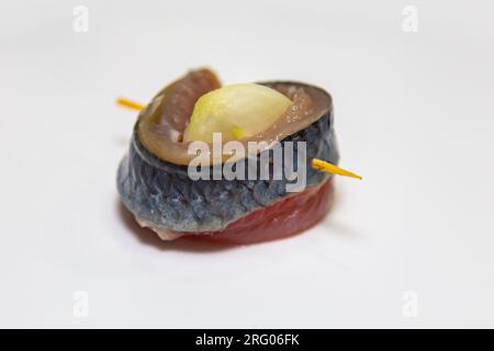 Traditionelle deutsche Geschirrrollen aus mariniertem Heringsfilet mit Zwiebelscheiben und Zitrone auf schwarzer Oberfläche. Stockfoto