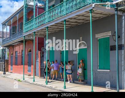 NEW ORLEANS, LA, USA - 6. AUGUST 2023: Tourgruppe unter der Galerie des historischen Felton Arms Building in der Chartres Street im French Quarter Stockfoto