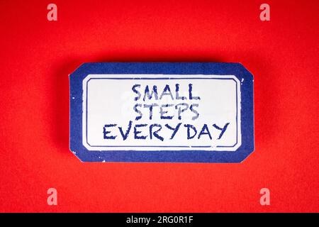 JEDEN TAG KLEINE SCHRITTE. Haftnotiz mit Text auf rotem Hintergrund. Stockfoto