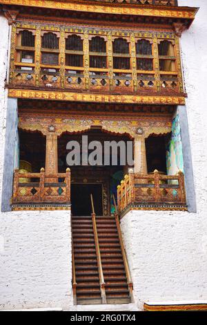 Steile Treppen führen zum Eingang auf einer oberen Ebene eines farbenfrohen Holzgebäudes innerhalb der Mauern des historischen Punakha Dzong im Königreich Bhutan Stockfoto