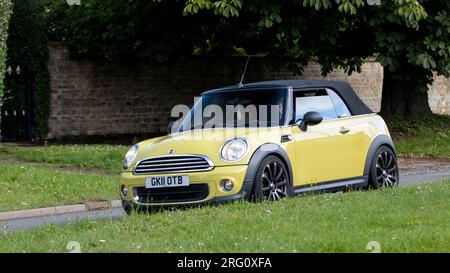 Whittlebury, Northants., Großbritannien - Aug 6. 2023. 2011 gelbes Cabriolet Mini, das durch ein englisches Dorf fährt. Stockfoto