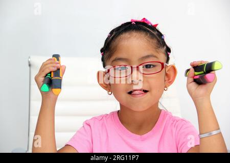 4-jähriges braunes Latina-Mädchen mit Autismus-Spektrum-Störung ASD wie Asperger, Rett und Heller zeichnet an einem Schreibtisch, spielt mit Farben allein, unsozial Stockfoto