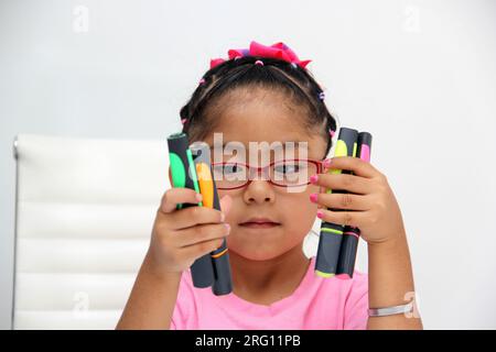 4-jähriges braunes Latina-Mädchen mit Autismus-Spektrum-Störung ASD wie Asperger, Rett und Heller zeichnet an einem Schreibtisch, spielt mit Farben allein, unsozial Stockfoto