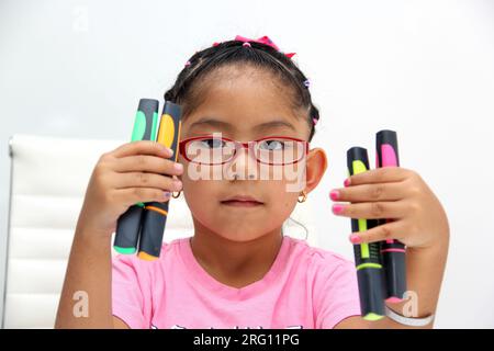 4-jähriges braunes Latina-Mädchen mit Autismus-Spektrum-Störung ASD wie Asperger, Rett und Heller zeichnet an einem Schreibtisch, spielt mit Farben allein, unsozial Stockfoto