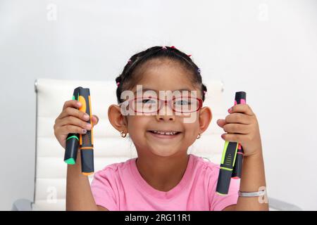 4-jähriges braunes Latina-Mädchen mit Autismus-Spektrum-Störung ASD wie Asperger, Rett und Heller zeichnet an einem Schreibtisch, spielt mit Farben allein, unsozial Stockfoto