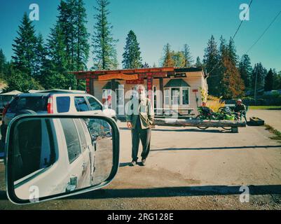 British Columbia, Kanada - 25. September 2021: Blick vom Seitenspiegel auf die Straßenszene und Landschaft in der Nähe der Ferry Landing Road, Balfour, BC Stockfoto