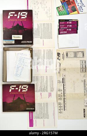 Flatlay des Inhalts des F-19 Stealth Fighter - Kampfsimulator; 1988 MS-DOS Computerspiel Cover Art und Verpackungsdesign. Stockfoto