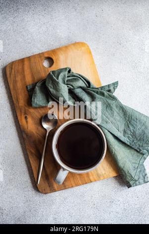 Draufsicht der Tasse Kaffee auf einem Holztablett mit Serviette und Löffel auf grauer Oberfläche Stockfoto