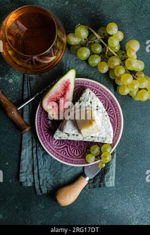 Von oben sortierte man leckere Snacks mit Käse und serviert auf einem Teller mit Trauben, Feigen und Getränk Stockfoto