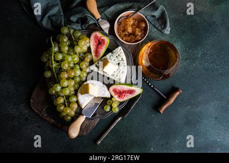 Top View mit leckeren Snacks mit Käse und serviert auf einem Teller auf einem Holzbrett mit Trauben, Feigen und Marmelade Stockfoto