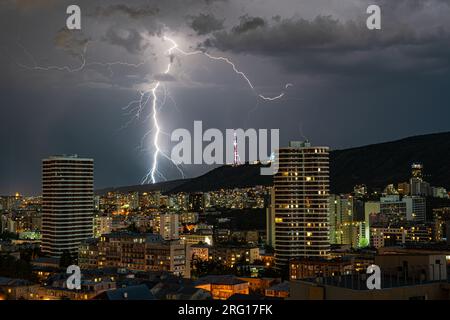 Dramatischer Himmel mit Lichtern in stürmischer Nacht über der Innenstadt von Tiflis Stockfoto