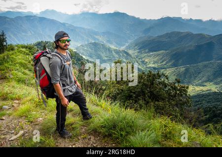 Oktober 14. 2022 Uttarakhand, Indien. Abenteuerlustiger Wanderer, roter Rucksack, verspiegelte Sonnenbrille, erkunden die Shivalik Mountains mit atemberaubendem Tal und m Stockfoto