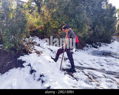 Oktober 14. 2022, Uttarakhand Indien. Abenteuerlicher allein-Trekker mit Bambus-Wanderstock und Rucksack erkundet die schneebedeckten Hügel der Mussoorie im Winter. Umarmen Stockfoto