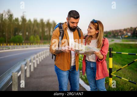 Ein glückliches lächelndes Paar schaut auf die Karte in der Stadt. Touristen machen Sightseeing in der Stadt. Stockfoto