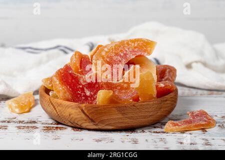 Getrocknete Papaya-Scheiben in einer Holzschüssel. Sonnengetrocknete, natürliche Papaya-Scheiben auf weißem Holzhintergrund Stockfoto