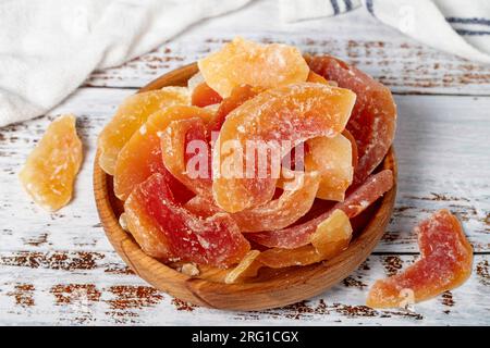 Getrocknete Papaya-Scheiben in einer Holzschüssel. Sonnengetrocknete, natürliche Papaya-Scheiben auf weißem Holzhintergrund. Schließen Stockfoto