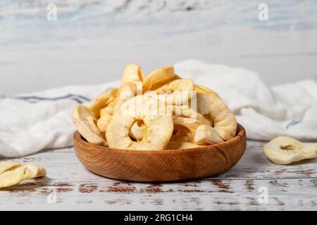 Getrocknete Apfelscheiben in einer Holzschüssel. Sonnengetrocknete Apfelscheiben auf weißem Holzhintergrund Stockfoto