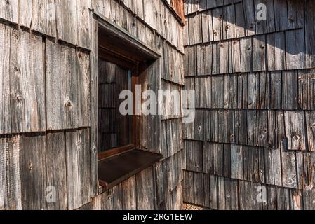 Slowenische Hüttenfenster und abgenutzte Holzgeflieste Fassade, selektiver Fokus Stockfoto