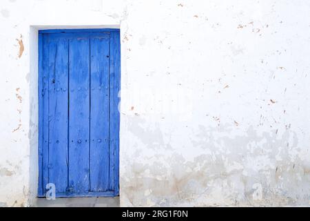 Weiße Wand mit blauer Holztür Stockfoto