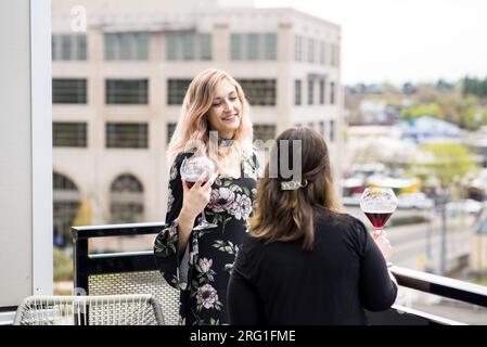 Zwei Frauen trinken Wein auf dem Balkon des Apartments Stockfoto