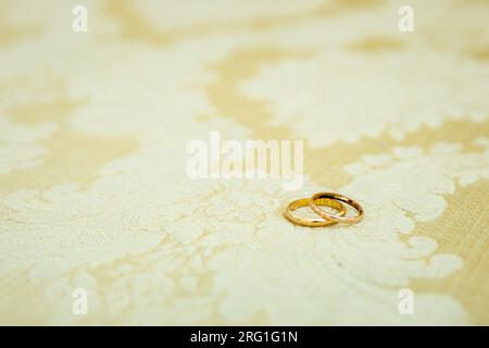 Detail mit goldenen Eheringen, einer übereinander, die die Liebe und Vereinigung eines Paares symbolisieren. Stockfoto