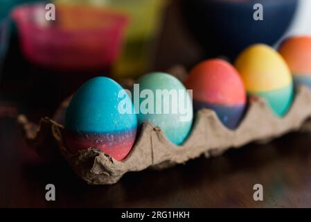 Eine Reihe bunt gefärbter Ostereier in einem Karton auf einem Tisch. Stockfoto