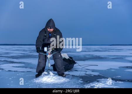 Fischer, die Löcher ins Eis bohren Stockfoto