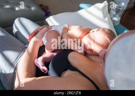 Blick aus dem Blickwinkel auf die Mutter, die ihr schlafendes Neugeborenes hält Stockfoto