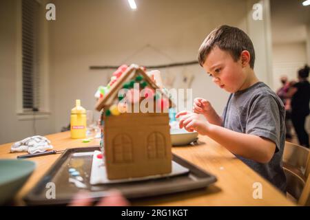 Seitenansicht eines Jungen, der ein Lebkuchenhaus dekoriert. Stockfoto