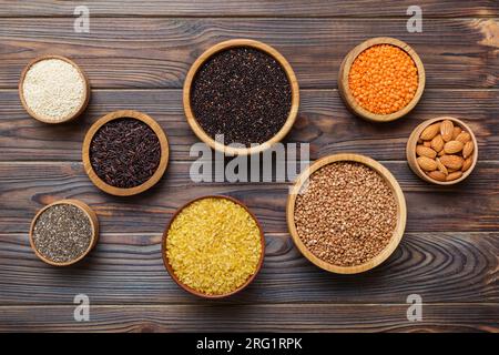 Verschiedene Superfoods in der kleinen Schüssel auf farbigem Hintergrund. Superfood wie Reis, Chia, Quinoa, Linsen, Nüsse, Sesamsamen, Mandeln. Kopierbereich der Draufsicht. Stockfoto