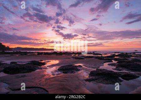 Wasserpfützen und Sandhaufen am Strand bei Sonnenuntergang. Drake Bay, Osa Peninsula, Costa Rica. Stockfoto