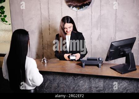 Frau berührte die Kreditkarte am Terminal des Kartenlesers, um für den Hotelservice zu bezahlen. Stockfoto