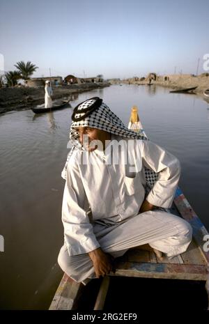 Marsh Araber. Südirak. Ein arabischer Mann im Boot mit adobe-Häusern, Flussufer der Flüsse Tigris und Euphrates, Sumpflandschaft von Hammar. Südirak 1980er HOMER SYKES Stockfoto