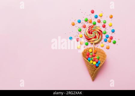 Waffelkonus voller traditioneller Süßigkeiten, die auf farbigen Hintergrund fallen, mit Platz für Kopien. Frohes Weihnachtsangebot. Stockfoto