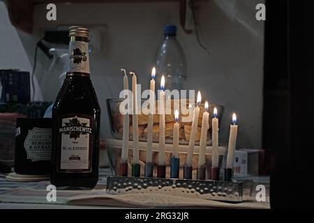 Beleuchtete Menora und eine Flasche Manischewitz auf einem Tisch während der Hannukah 2022 Stockfoto