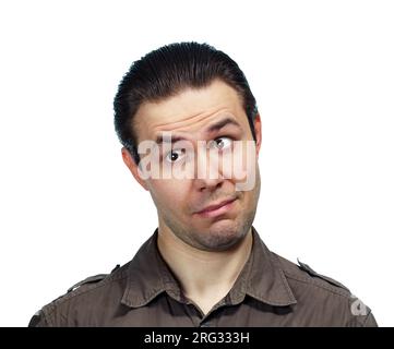 Ein junger, überraschter Mann, der wegsieht, ein emotionales Porträt auf weißem Hintergrund Stockfoto