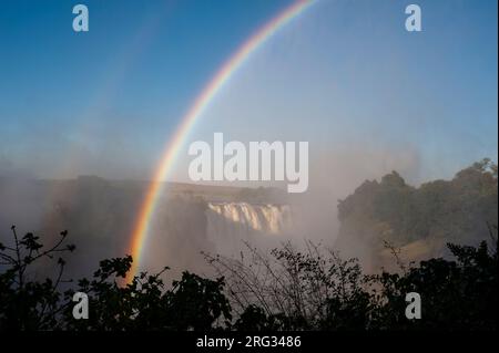 Ein doppelter Regenbogen über den nebligen Victoria Falls. Victoria Falls National Park, Simbabwe. Stockfoto