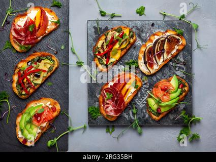 Set aus verschiedenen Bruschetta mit verschiedenen Belägen für den Urlaub auf dem Steinbrett. Draufsicht. Partykulinarisches Konzept. Stockfoto