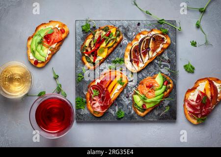 Set aus verschiedenen Bruschetta mit verschiedenen Belägen für den Urlaub auf dem Steinbrett. Draufsicht. Partykulinarisches Konzept. Stockfoto