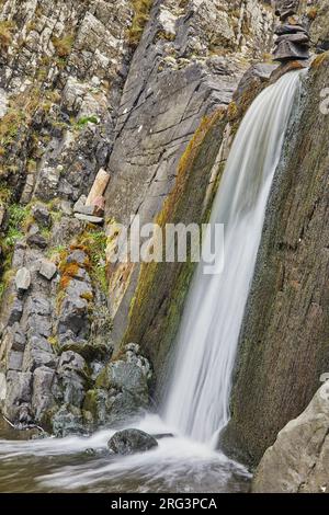 Ein Wasserfall stürzt auf einer senkrechten Klippe an der Küste von Speke's Mill Mouth in der Nähe des Hartland Quay, der Atlantikküste von Devon, Großbritannien, ab. Stockfoto