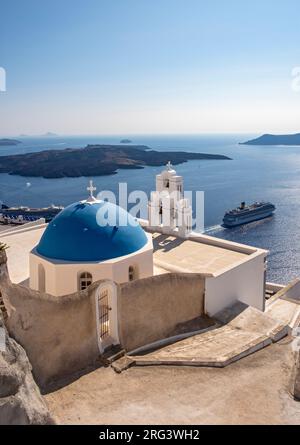 Berühmte Kirche mit blauer Kuppel und Glocke (drei Glocken von Fira) mit Costa Fortuna Kreuzfahrtschiff, katholische Dormitionskirche, Firostefani, Santorin, Griechenland Stockfoto