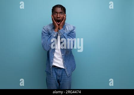 Schockierter glücklicher afrikaner mit Dreadlocks in Jeansjacke gewann im Lotto Stockfoto