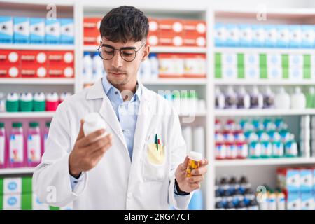Junger hispanic-Mann Apotheker hält Pillen Flaschen in der Apotheke Stockfoto