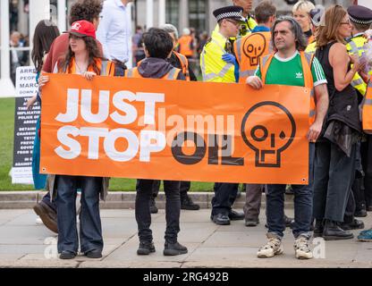 Just Stop Oil-Aktivisten mit großem Banner in Zentral-London, die sich für die Regierung einsetzen, alle zukünftigen Lizenzen und die Produktion fossiler Brennstoffe zu stoppen. Stockfoto