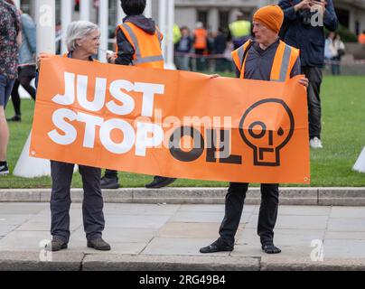 Just Stop Oil-Aktivisten mit großem Banner in Zentral-London, die sich für die Regierung einsetzen, alle zukünftigen Lizenzen und die Produktion fossiler Brennstoffe zu stoppen. Stockfoto