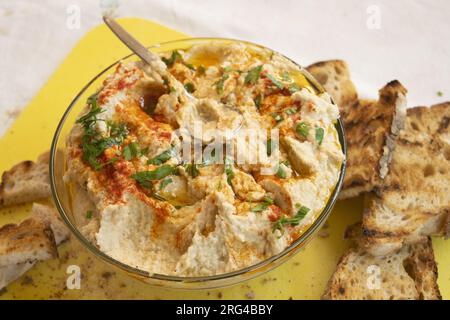 Hausgemachter Hummus mit Paprika in einer Glasschüssel und getoastetem Brot Stockfoto