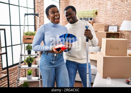 Ein junges afroamerikanisches Paar zieht in ein neues Haus und wählt Wände, die wütend und verrückt sind, frustriert und wütend, vor Wut schreiend. Wut und Stockfoto