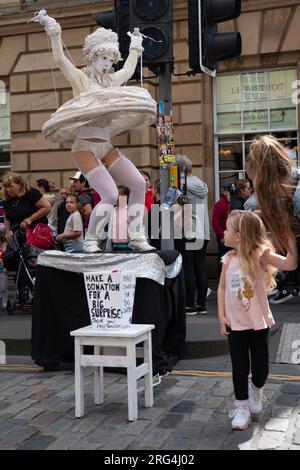 Edinburgh, Schottland, Großbritannien. 7. August 2023. Viele Schauspieler werben für ihre Shows und Straßenkünstler unterhalten die Öffentlichkeit auf der Royal Mile am zweiten Tag des Edinburgh Fringe Festivals. BILD: Die Straßenkünstlerin Lady Whistle überrascht heute einen jungen Besucher der Royal Mile. Iain Masterton/Alamy Live News Stockfoto